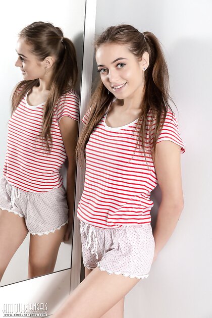 Thin teen Angelina undresses on her bed in front of a mirror